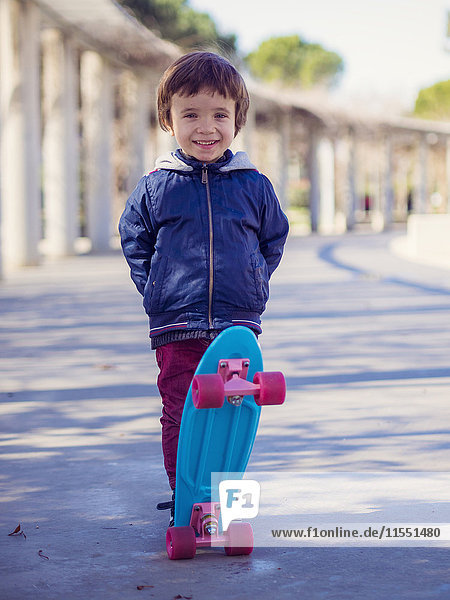Portrait of smiling little boy with skateboard