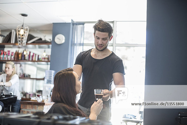Frau im Friseursalon erhält eine Tasse Kaffee