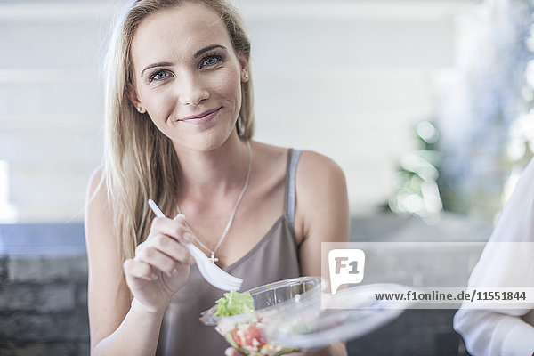 Junge Geschäftsfrau isst Salat zum Mittagessen