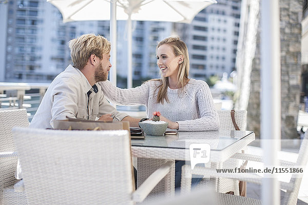 Ein glückliches junges Paar sitzt in einem Café im Freien.