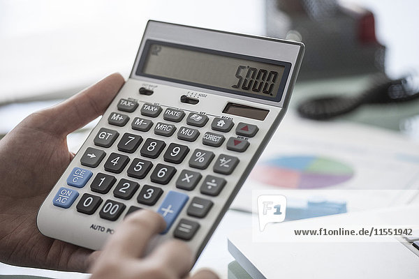 Close-up of man using a calculator in office