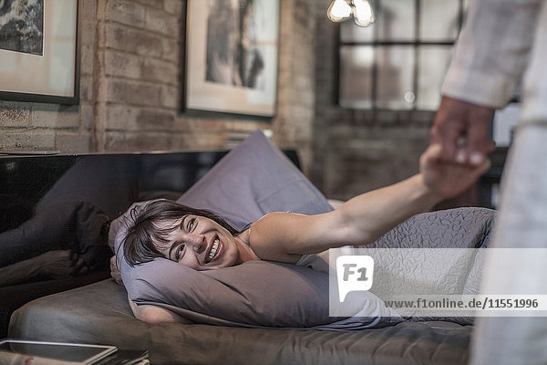 Lächelnde Frau im Bett mit Blick auf den Ehemann