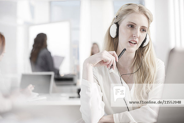 Portrait of woman at desk in office wearing headphones
