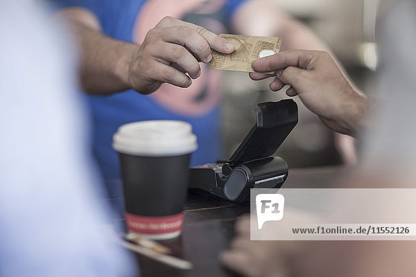 Person paying with credit card at coffee shop