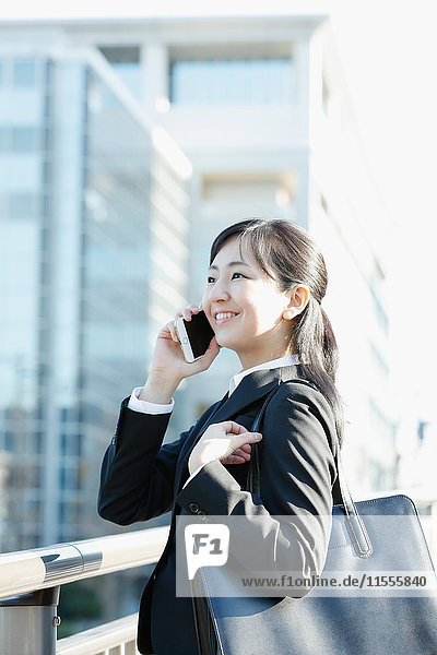 Junge japanische Geschäftsfrau am Telefon in der Innenstadt von Tokio