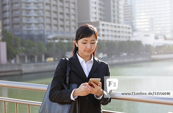 Junge japanische Geschäftsfrau mit Telefon in der Innenstadt von Tokio
