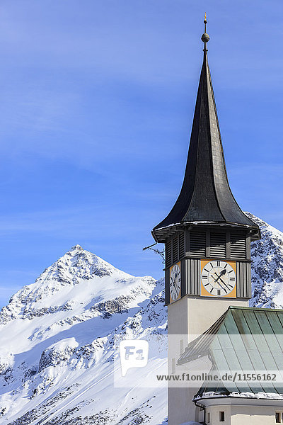Der typische Alpenglockenturm umrahmt die schneebedeckten Gipfel  Langwies  Bezirk Plessur  Kanton Graubünden  Schweizer Alpen  Schweiz  Europa