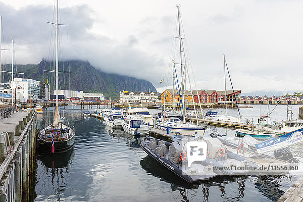 Wolken auf felsigen Gipfeln umrahmen die Boote im Hafen des Fischerdorfs Svolvaer  Vagan  Lofoten  Norwegen  Skandinavien  Europa