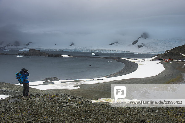 Tourist beim Fotografieren von einem Aussichtspunkt über der Halbmondinsel,  Süd-Shetland-Inseln,  Antarktis,  Polarregionen