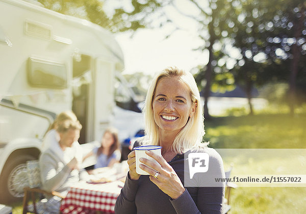 Portrait lächelnde Frau trinkt Kaffee draußen im sonnigen Wohnmobil
