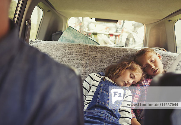 Müde Schwestern schlafen auf dem Rücksitz des Autos