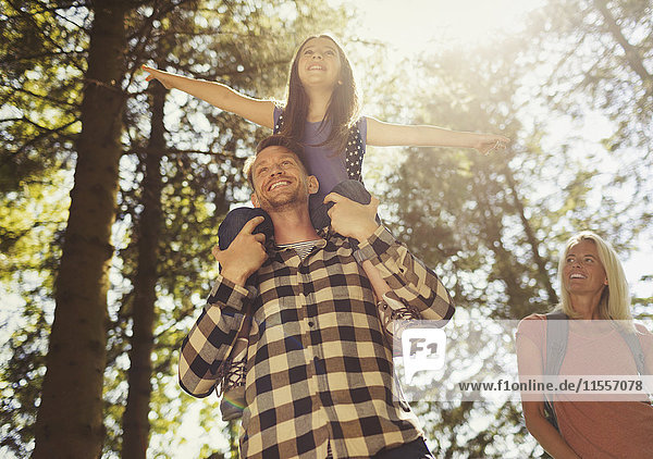 Vater trägt Tochter auf Schultern  Wandern in sonnigen Wäldern