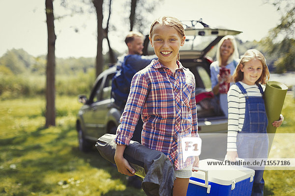 Portrait lächelnde Familie beim Entladen von Campingausrüstung aus dem Auto