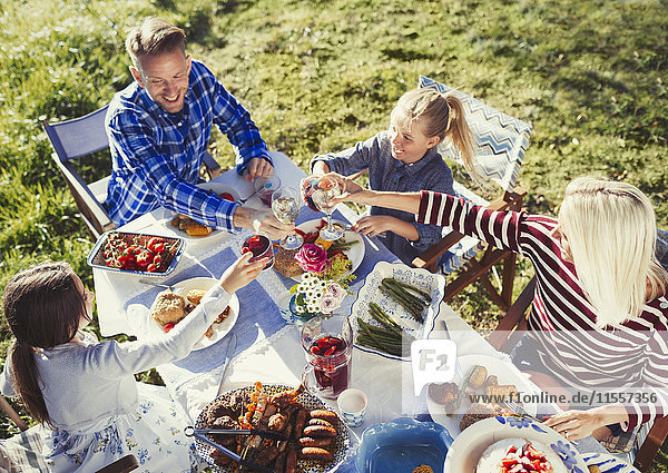 Familientoast mit Wein und Wassergläsern am sonnigen Mittagstisch auf der Terrasse