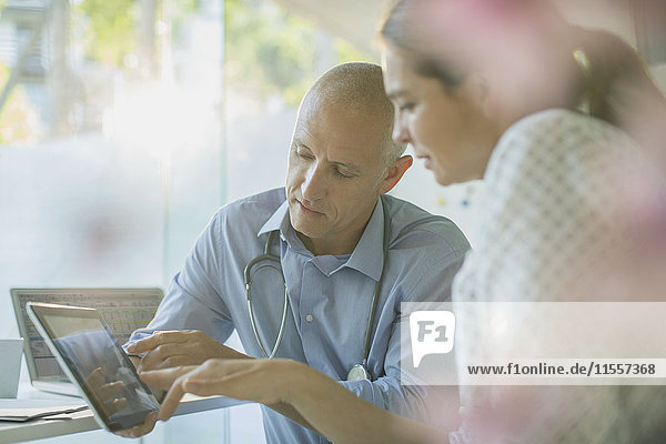 Male doctor showing digital tablet to female patient in doctor’s office
