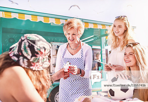 Senior Unternehmerin serviert Eiscreme für junge Frauen außerhalb des sonnigen Speisewagens