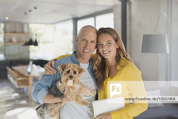 Portrait smiling mature couple hugging with dog in living room