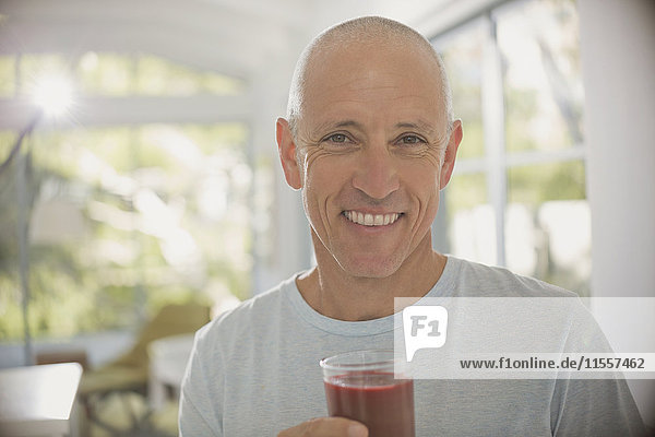 Portrait smiling  confident mature man drinking healthy fruit smoothie