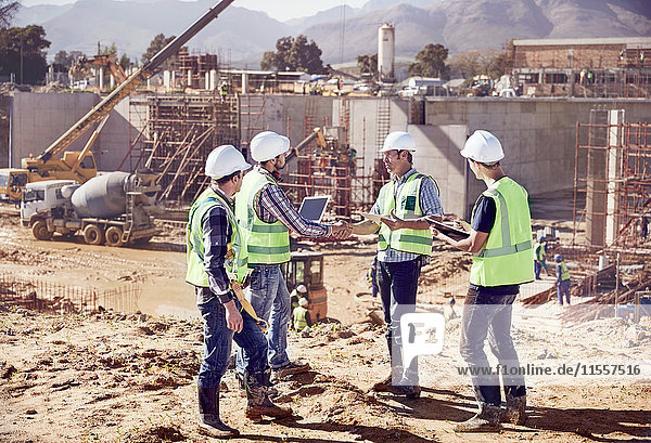 Bauarbeiter und Ingenieure beim Händeschütteln  Treffen auf der sonnigen Baustelle