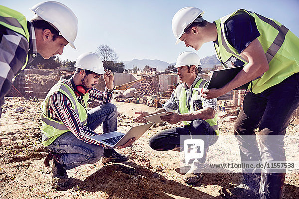 Bauarbeiter und Ingenieure mit digitalen Tabletts auf der sonnigen Baustelle