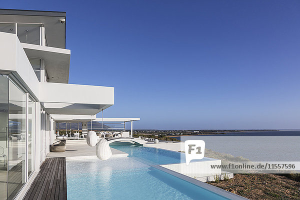 Sonniges  ruhiges  modernes  luxuriöses Haus mit Pool und Meerblick unter blauem Himmel.