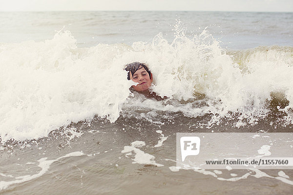 Wellen plätschern um einen Jungen  der im Sommer im Meer schwimmt