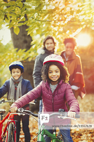 Portrait lächelndes Mädchen Radfahren mit der Familie im sonnigen Herbstpark