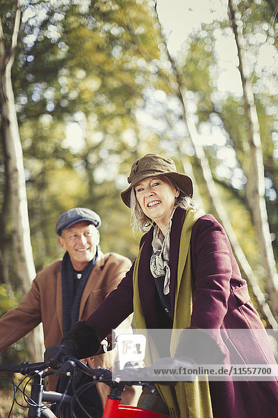 Portrait lächelndes Seniorenpaar Radfahren im Herbstpark