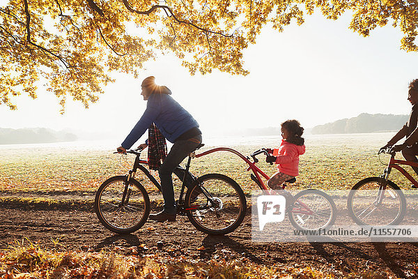 Vater und Tochter Radfahren mit Anhänger im sonnigen Herbstpark
