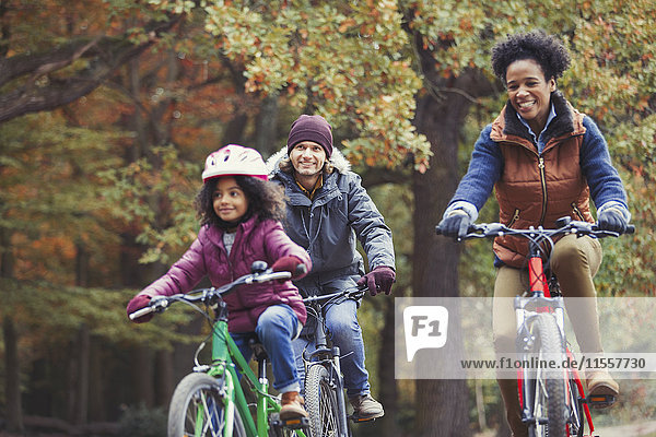 Verspieltes junges Familienradfahren im Herbstpark