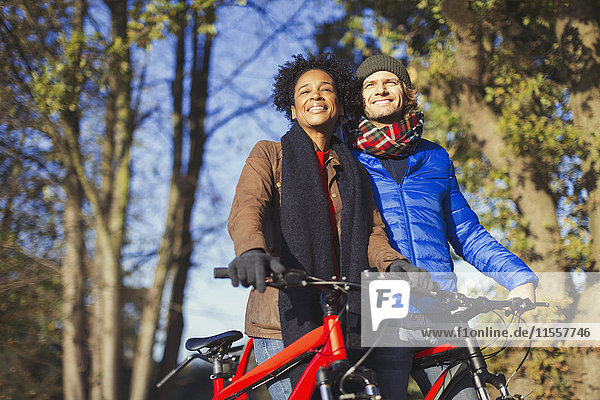 Smiling couple with bicycles in sunny autumn park