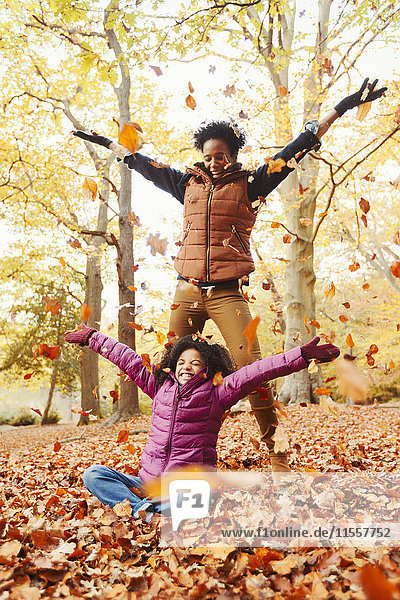 Verspielte Mutter und Tochter beim Herbstlaubwerfen im Park