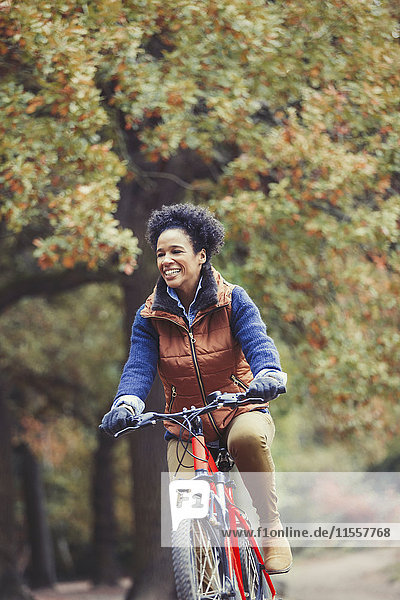 Lächelnde Frau beim Radfahren im Herbstpark
