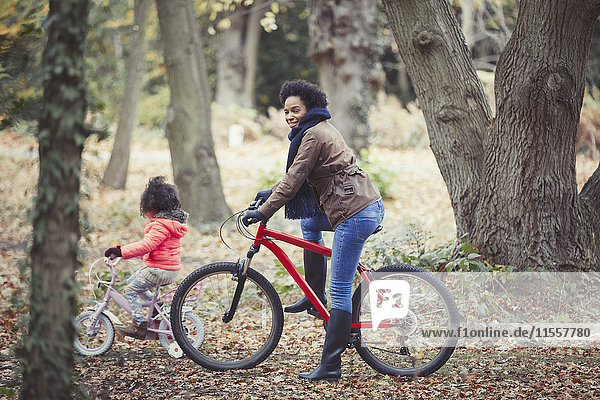 Mutter und Tochter Radfahren im Herbstwald