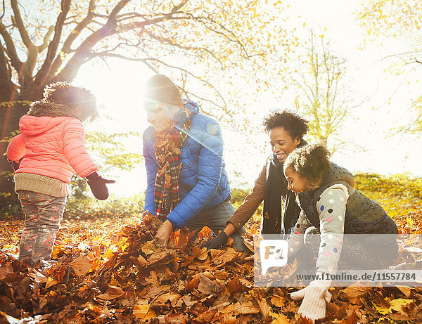 Junge Familie spielt im Herbstlaub im sonnigen Park