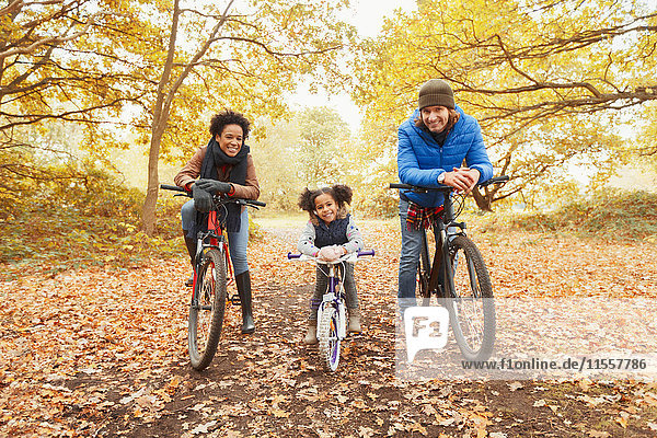 Portrait smiling young family bike riding in autumn park