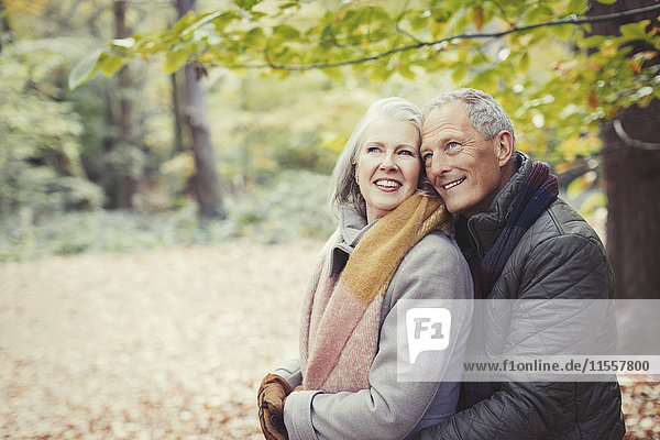 Lächelndes Seniorenpaar umarmt im Herbstpark