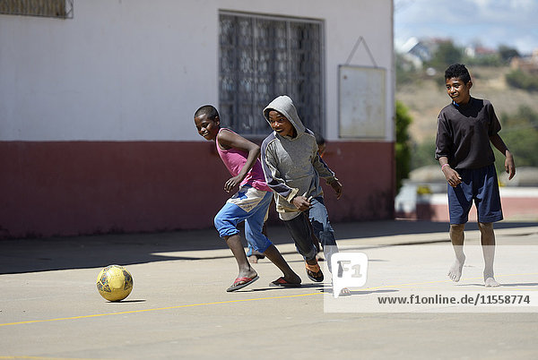 Madagaskar  Fianarantsoa  Junge spielt Fußball auf dem Schulhof