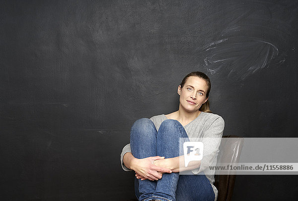 Porträt einer lächelnden Frau vor der Tafel sitzend