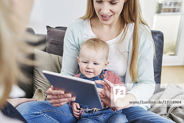 Mother and baby girl at home looking at tablet