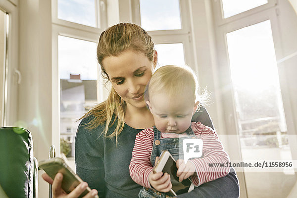 Mutter und kleines Mädchen mit Mobiltelefonen