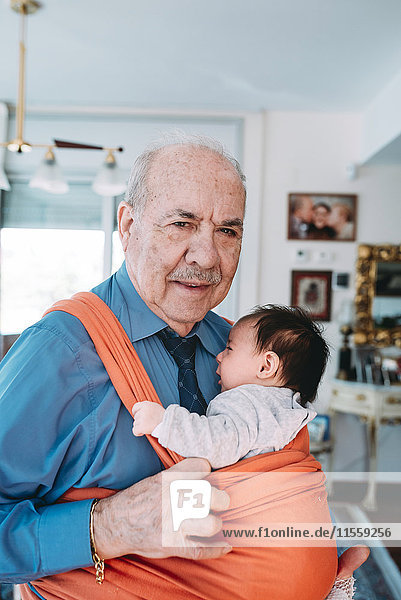 Portrait of great-grandfather carrying baby in a baby sling