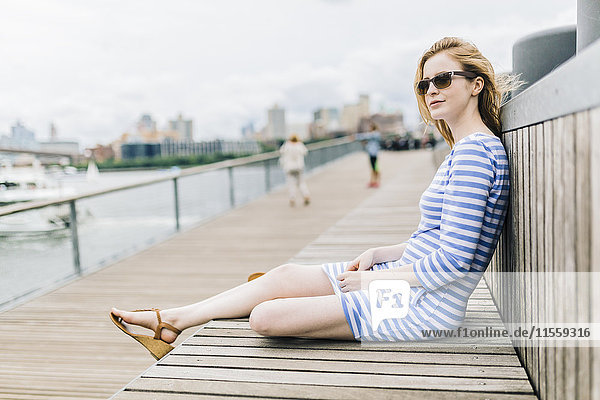 Junge Frau am Pier sitzend
