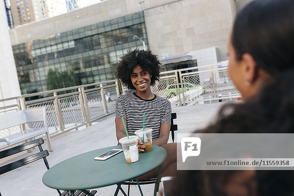 Portrait of smiling woman sitting at pavement cafe talking to her friend