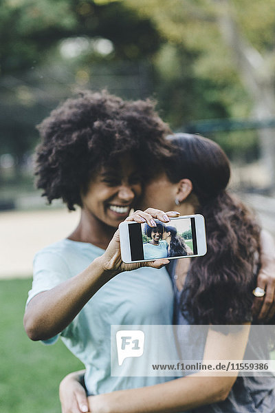 Two women taking selfiewith smartphone in a park