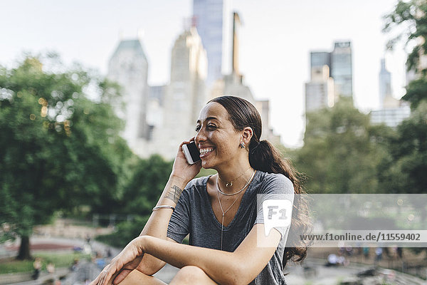 USA  Manhattan  Porträt einer jungen Frau am Telefon im Central Park