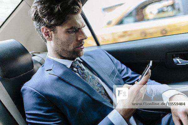Geschäftsmann im Taxi sitzend  mit Smartphone