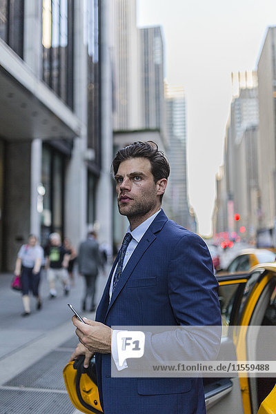 Businessman exiting yellow taxi in Manhattan