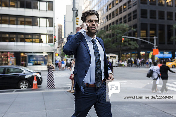 Handsone Geschäftsmann in Eile läuft durch Manhattan,  mit Smartphone