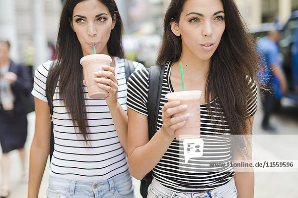 USA  New York City  two twin sisters on the go in Manhattan with takeaway drink